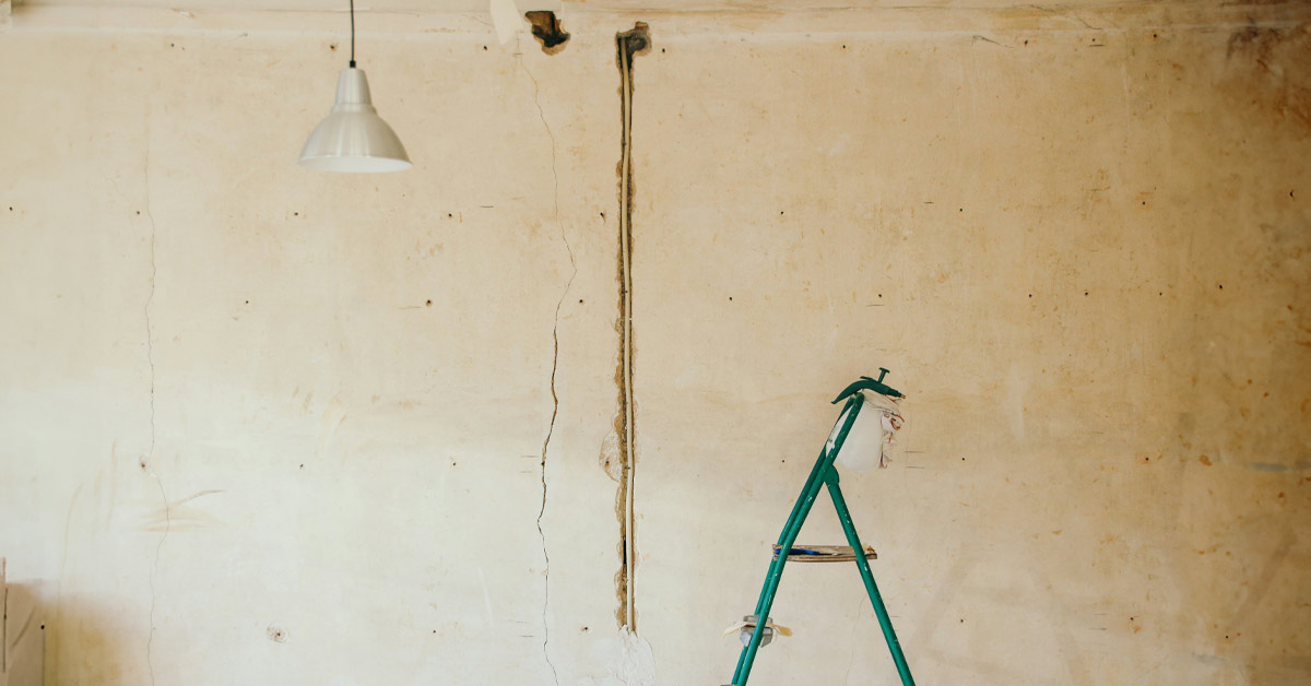 Vor einer unverputzten Wand steht eine Leiter, Renorvierungsarbeiten werden dargestellt